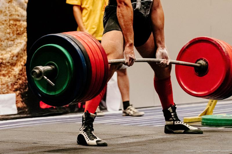 Powerlifting and Olympic lifting are strength-based sports, but their movements, objectives, and techniques differ significantly. The three primary lifts in powerlifting are the squat, bench press, and deadlift. Each of these lifts aims to lift the maximum weight possible. The sport emphasizes brute strength and places less emphasis on the lifter's quickness or fluidity of movement. Olympic lifting, also called weightlifting, consists of two lifts: the snatch and the clean and jerk. Athletes must transfer the barbell from the floor to overhead in one or two swift movements. Olympic lifting places a premium on strength, speed, flexibility, and coordination, as lifters must execute activities quickly and accurately.